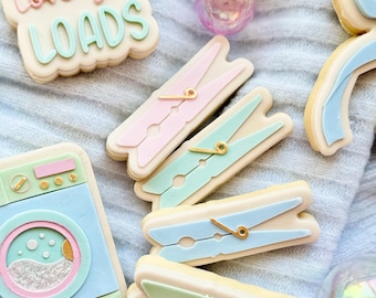 May include: A set of decorated sugar cookies featuring a washing machine, clothes pegs and a cookie with the text "Mum love you loads".