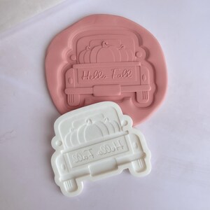 May include: A pink silicone mould of a white pickup truck with pumpkins in the bed. The truck has the words "Hello Fall" on the back.