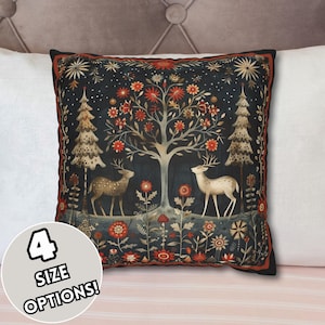 May include: A decorative throw pillow with a dark blue background featuring a stylized tree with red flowers, two deer, and a forest scene. The pillow has a red, gold, and white border.