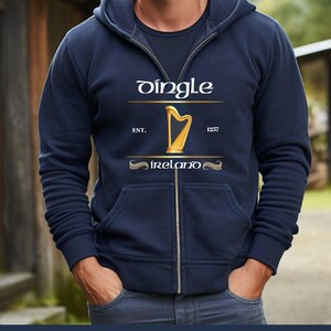 May include: Navy blue zip-up hoodie with a gold harp graphic and the word "Dingle" in white. The text "EST. 1257 Ireland" is also displayed. The hoodie has a drawstring hood and front pockets.