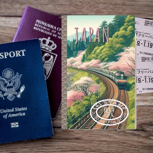 May include: A blue United States passport and a purple passport are next to a travel journal with the word "JAPAN" on the cover. The journal features a train traveling through a scenic landscape with cherry blossoms.