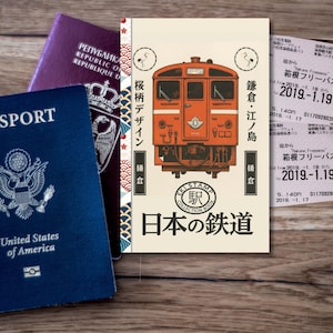 May include: A travel-themed image featuring a blue United States passport, a purple passport, and a Japanese train-themed notebook. The notebook has an orange train illustration and Japanese text. Train tickets are also visible.