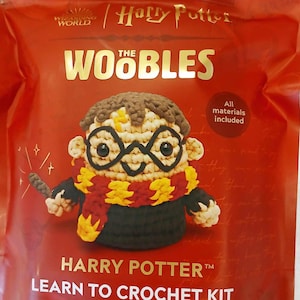 May include: A Harry Potter themed crochet kit featuring a crocheted Harry Potter character with glasses and a scarf. The kit includes all materials needed to crochet the character. The packaging is red with gold lettering and the words "Harry Potter" and "Learn to Crochet Kit for Beginners".