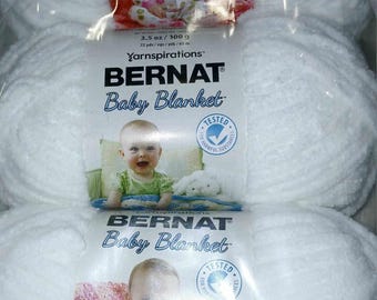 May include: Three packages of Bernat Baby Blanket yarn. Each package features a baby and a plush toy. The packaging includes the text "Baby Blanket" and "Tested for Harmful Substances". Each package contains 3.5 oz / 100 g of yarn.