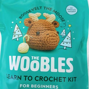 May include: A turquoise blue bag with a crocheted moose head on the front. The bag says "Roosevelt the Moose" and "The Woobles Learn to Crochet Kit for Beginners". The bag also says "All materials included".