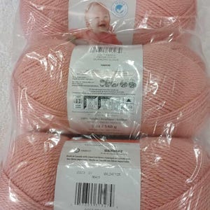 May include: Three skeins of Bernat Softee Baby yarn in Soft Peach. Each skein is 5 oz (140 g) and made of 100% acrylic. The packaging features a baby and product information.