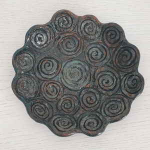 May include: A ceramic dish with a scalloped edge and a design of swirling circles in shades of blue and brown.