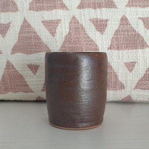 May include: A dark brown ceramic mug with a textured surface.