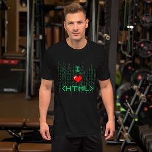 Peut inclure: T-shirt noir avec un motif vert et rouge. Le motif présente le texte "I <3 HTML" dans un style pixelisé, avec un fond vert en forme de matrice. Le t-shirt est à manches courtes et a un col rond.