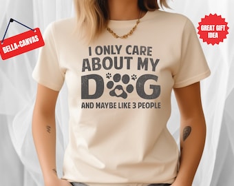 Peut inclure: Un t-shirt beige avec le texte "I only care about my dog and maybe like 3 people" imprimé en noir avec un graphique d'empreinte de patte.