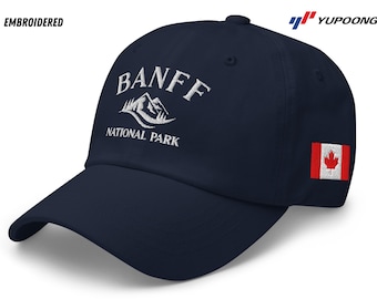 May include: A navy blue baseball cap with white embroidered text that reads "Banff National Park" and a white mountain graphic. The cap also has a small red and white Canadian flag patch on the side.