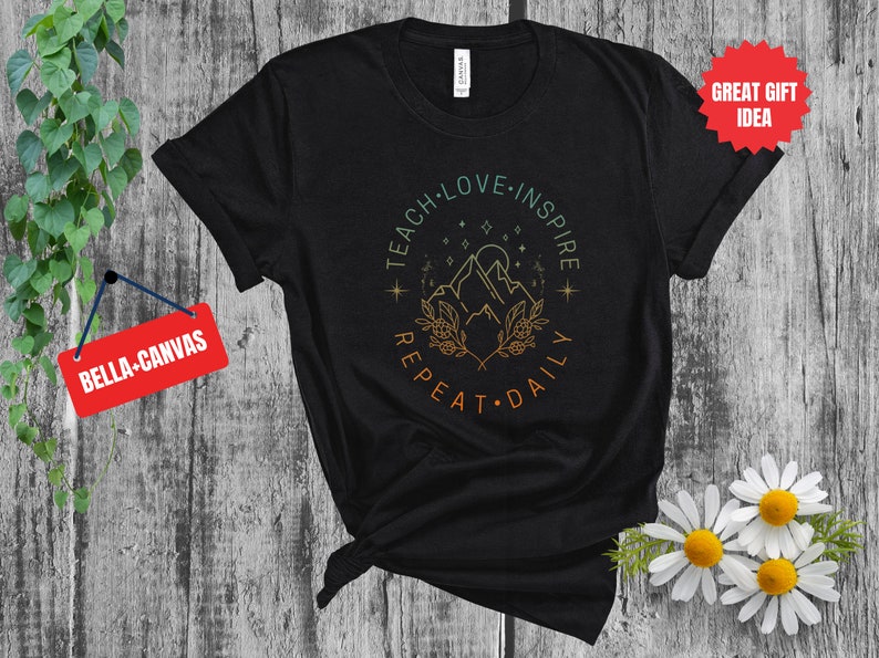 May include: Black t-shirt with a graphic design of a mountain range with stars and the text "Teach Love Inspire Repeat Daily".