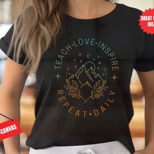 May include: Black t-shirt with a graphic design of mountains, stars, and a floral design. The text "Teach Love Inspire Repeat Daily" is written around the graphic.