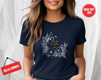 Puede incluir: Camiseta azul marino con un diseño floral blanco y el texto "It's ok to not be ok."