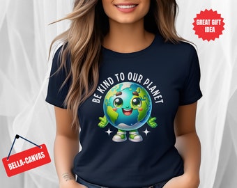 Puede incluir: Una camiseta azul marino con un gráfico blanco de una Tierra de dibujos animados sonriente con el texto "Be Kind to Our Planet".