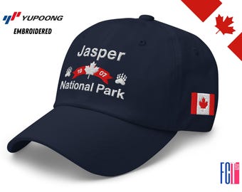 May include: Navy blue baseball cap with embroidered text "Jasper National Park" and a Canadian maple leaf design. Features a small Canadian flag patch on the side. The cap has a curved brim and a top button.