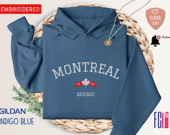 May include: A blue hooded sweatshirt with the text "MONTREAL EST. 1904 QUEBEC" embroidered on the front. The text is in white with a red maple leaf logo.