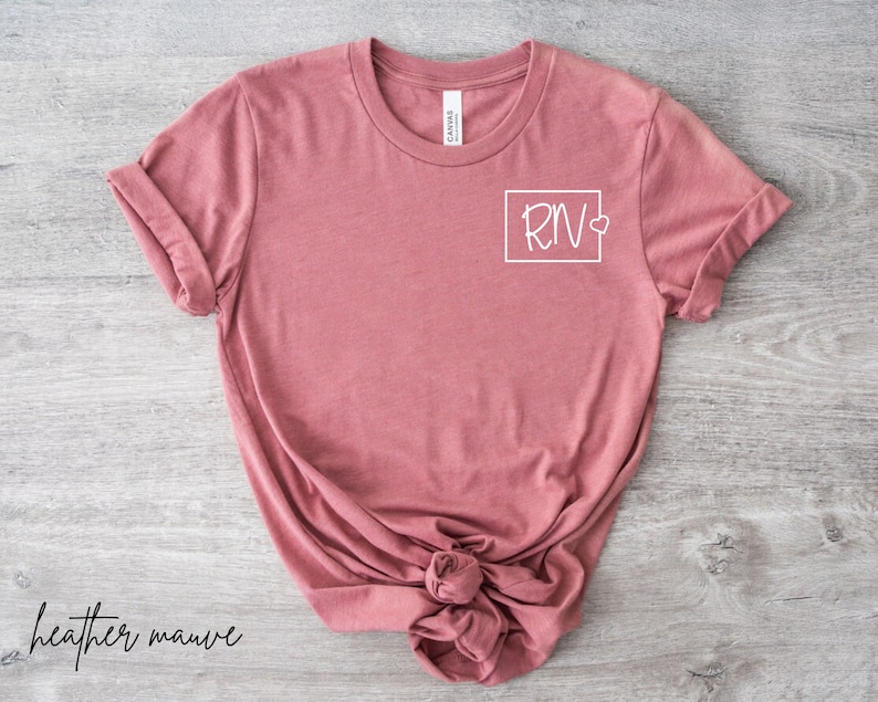 May include: Heather mauve t-shirt with a white graphic of a square containing the letters "RN" and a small heart.