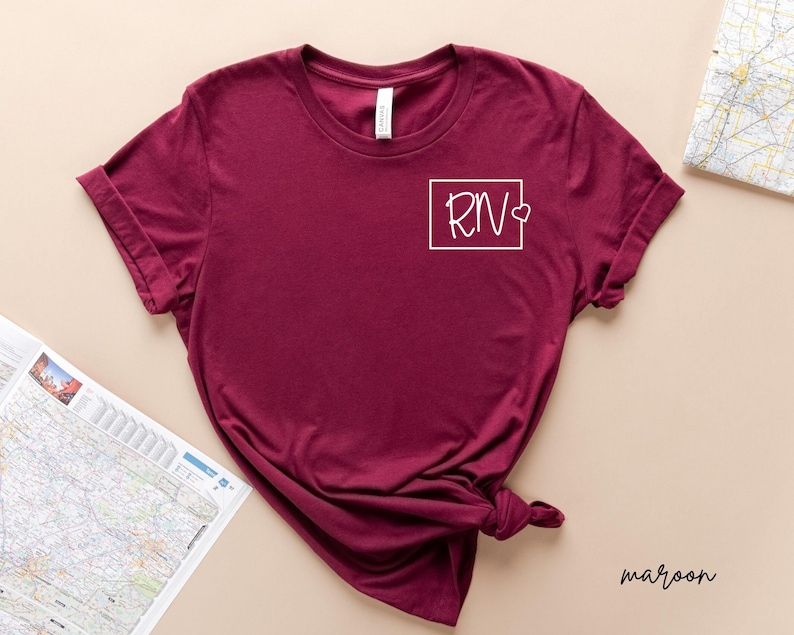 May include: Maroon t-shirt with a white square graphic that says "RN" with a small heart next to it.