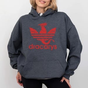 May include: A dark gray hoodie with a red dragon logo and the text "dracarys" printed on the front.
