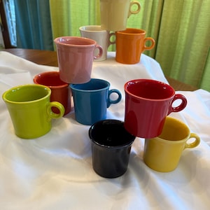 May include: A set of three ceramic mugs with a speckled, matte finish in cream, light grey, and dark grey. Each mug has a simple, minimalist design, suitable for coffee or tea.