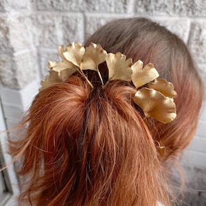 May include: Gold ginkgo leaf hair clip. The clip is made of metal and has a natural ginkgo leaf design. It is a beautiful and unique hair accessory.