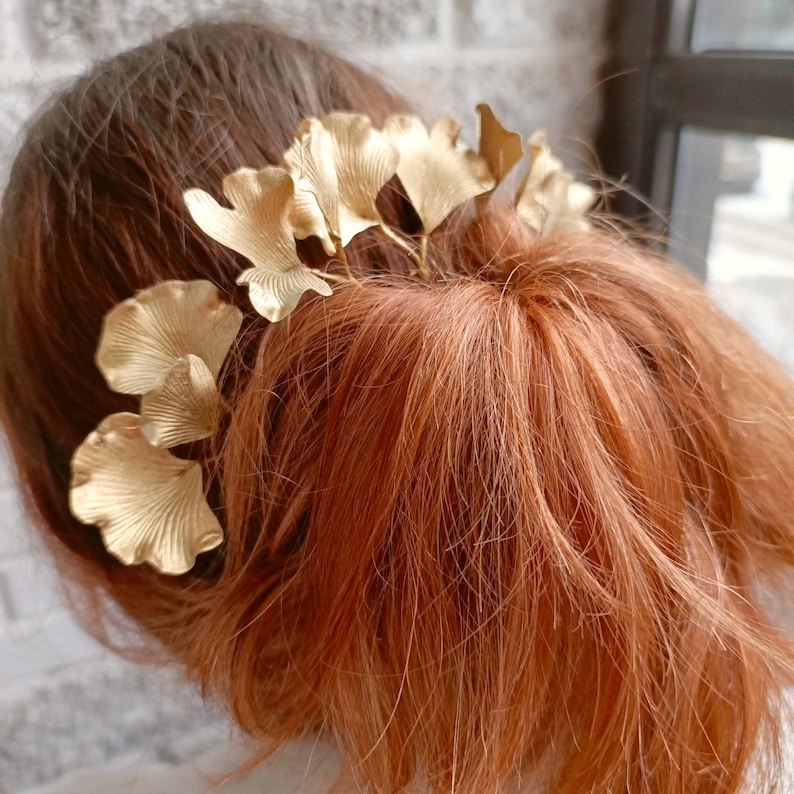 May include: Gold hair comb with a ginkgo leaf design. The comb is made of metal and has a delicate, feminine look.