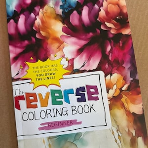 May include: A paperback book titled The Reverse Coloring Book Beginner with a vibrant watercolor floral cover in shades of magenta, orange, and blue. A yellow starburst graphic contains the text THE BOOK HAS THE COOLOORS, YOU DRAW THE LINES!