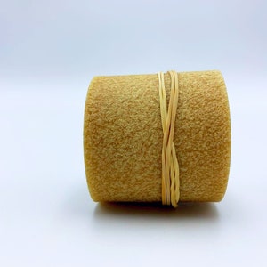 Op de afbeelding: Een ronde, beige kaars met een natuurlijk, getextureerd oppervlak. De kaars is vastgebonden met een dun, beige touwtje.