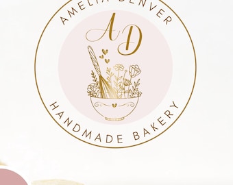 May include: A logo for Amelia Denver Handmade Bakery, featuring a gold-colored circular design with text and illustrations. The logo includes the text "AMELIA DENVER" and "HANDMADE BAKERY". The central design is a bowl with baking tools and flowers.
