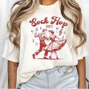 May include: White t-shirt with a red graphic of a couple dancing with the text "Sock Hop 1990's" and musical notes.