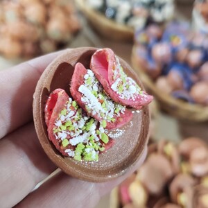 Puede incluir: Un peque&ntilde;o plato de arcilla marr&oacute;n con tres obleas de caramelo rosa y blanco cubiertas con chispas verdes y blancas.