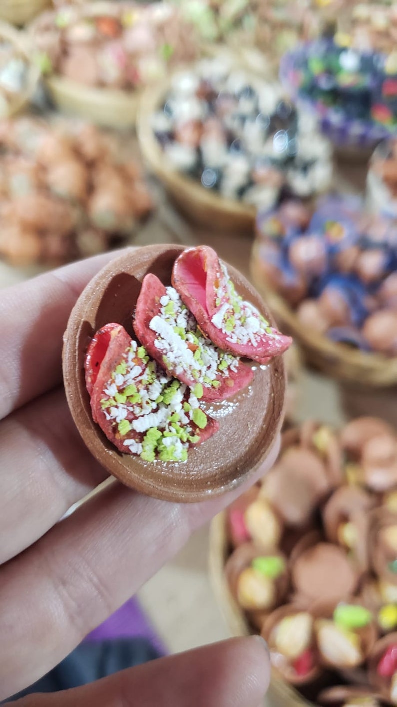 Puede incluir: Un peque&ntilde;o plato de arcilla marr&oacute;n con tres obleas de caramelo rosa y blanco cubiertas con chispas verdes y blancas.