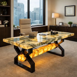 Op de afbeelding: Een rechthoekig bureau met een gepolijst, doorschijnend groen en geel onyx stenen blad met natuurlijke aders. Het onderstel bestaat uit zwarte metalen X-vormige poten verbonden door een centraal, verlicht rechthoekig blok van gloeiende gele onyx.