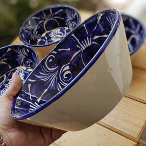 May include: Three white ceramic bowls with blue floral designs. The bowls are hand-painted with intricate details and have a glossy finish.
