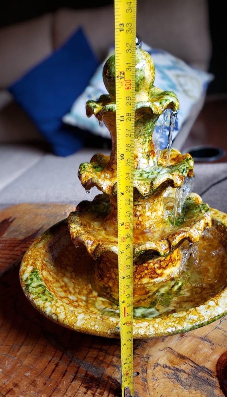 May include: A three-tiered ceramic fountain with a yellow, green, and brown glaze. The fountain is 30.5 cm tall and features a cascading water design.