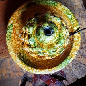 May include: A ceramic fountain with three tiers, featuring a green and yellow glaze. The fountain has a round, open top and a small hole in the centre.