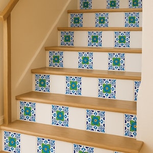 Puede incluir: Escalera de madera con contrahuellas blancas adornadas con baldosas cuadradas. Cada baldosa presenta un diseño floral azul y verde. Los escalones son de madera clara, creando un ambiente luminoso y acogedor.