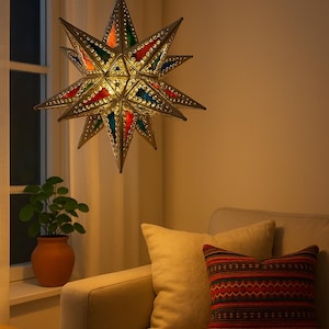 Puede incluir: Lámpara colgante en forma de estrella con paneles de vidrieras de colores. El marco metálico es plateado y la luz cuelga de una cadena. Sobre un sofá beige con cojines decorativos, creando un ambiente cálido.