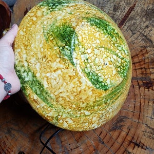 May include: A large, round bowl with a yellow, green and white marbled design. The bowl is made of ceramic and has a glossy finish.