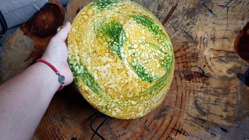 May include: A large, round bowl with a yellow, green and white marbled design. The bowl is made of ceramic and has a glossy finish.