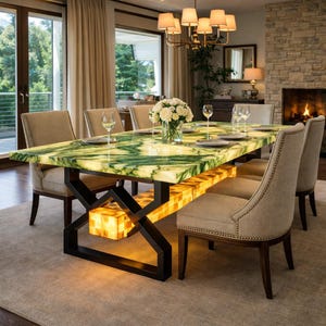 Puede incluir: Una mesa de comedor moderna con una tapa de mármol verde y blanco, sostenida por una base de metal negro. La mesa está iluminada desde dentro y rodeada de sillas tapizadas. Una lámpara de araña cuelga sobre la mesa.