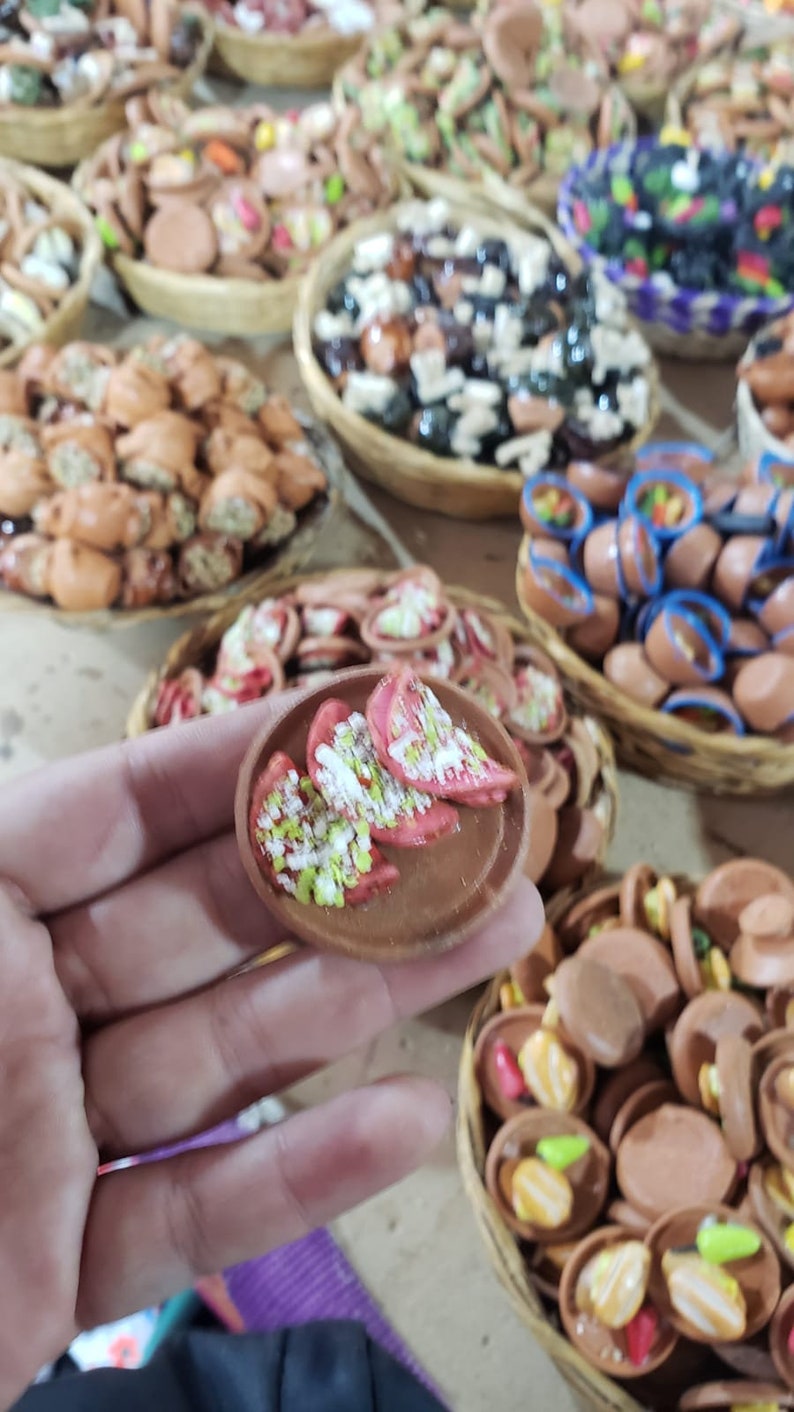 Puede incluir: Un primer plano de un peque&ntilde;o plato de cer&aacute;mica pintado a mano con un dise&ntilde;o rojo y blanco. El plato est&aacute; lleno de peque&ntilde;as piezas de cer&aacute;mica blancas y verdes. El plato est&aacute; siendo sostenido en la mano de una persona.