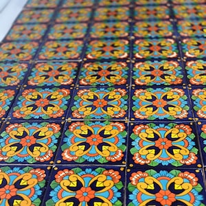 May include: A close-up of a repeating pattern of colorful ceramic tiles. The tiles are square and feature a floral design with blue, yellow, orange, and white accents on a dark blue background.