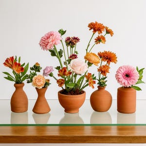 Puede incluir: Una colección de jarrones de terracota, cada uno con un arreglo diferente de flores coloridas. Las flores incluyen flores naranjas, rosas y moradas, creando una exhibición vibrante. Los jarrones varían en forma y tamaño.