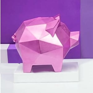 May include: A pink geometric piggy bank made of triangles. The piggy bank is sitting on a white platform.