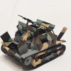 May include: A detailed model of a military tank with a camouflage pattern in shades of brown, tan, gray, and blue. The tank features a gun and other military details, set against a white background.