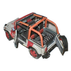 Może przedstawiać: Papierowy model Jeepa w kolorze białym, czerwonym i czarnym z klatką bezpieczeństwa, otwartymi drzwiami i tylną klapą. Jeep ma numer "18" na boku.