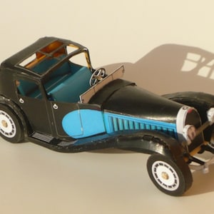 May include: A black and blue model car with a detailed interior and a blue stripe along the side. The car has a black roof and a black steering wheel.