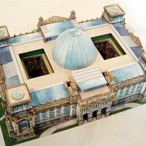 May include: A detailed paper model of a building with a central dome and multiple rectangular sections. The model features intricate architectural details, including columns, windows, and decorative elements. The color palette includes beige, blue, and green.